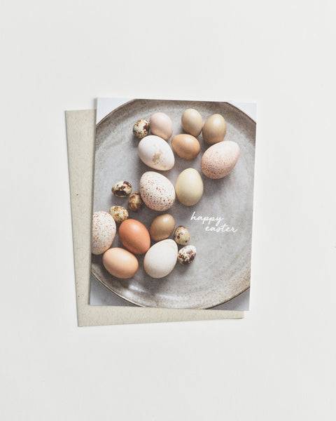 Photo greeting card of assorted brown and white eggs in various patterns and sizes with words “happy easter” in cursive.